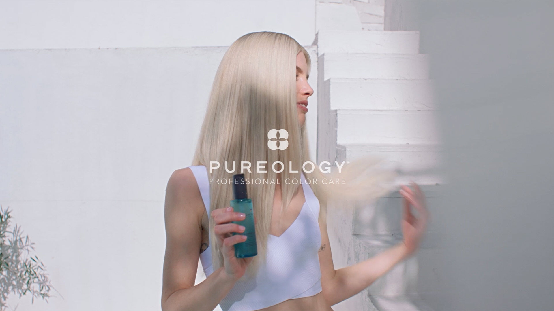 'Pureology Professional Color Care logo over an image of a person holding a bottle of Pureology Strength Cure product with long blonde hair in a bright white setting.'