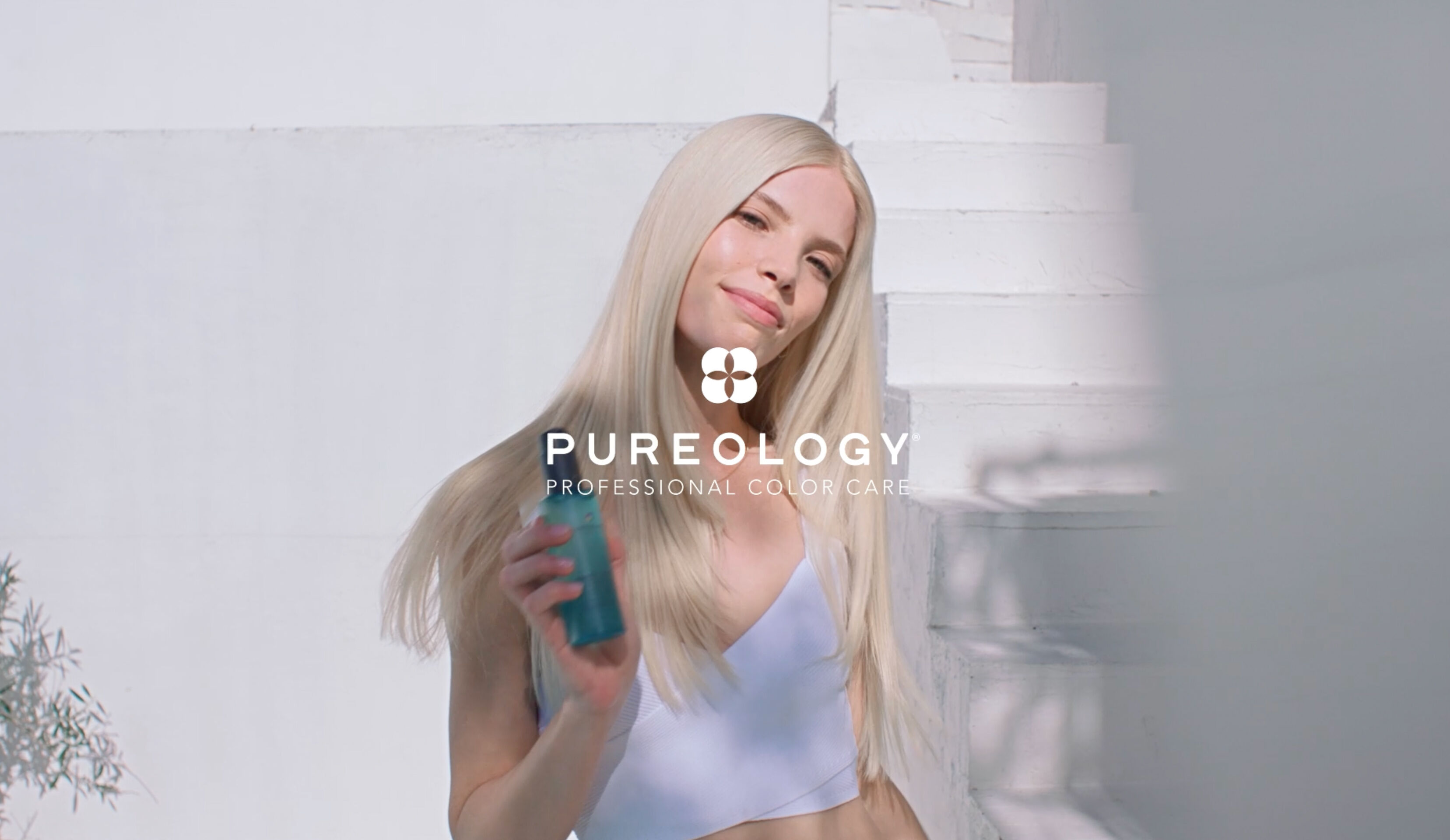 Pureology Professional Color Care logo over a woman with long blonde hair holding a Strength Cure Dream Healer Serum.